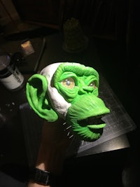 a hand holding a green monkey mask