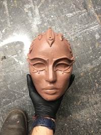 a person holding a brown clay mask