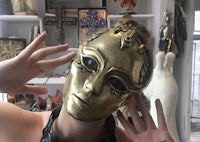 a woman wearing a gold mask in a room