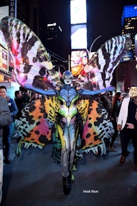 a woman dressed as a butterfly walks down the street in times square