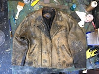 a leather jacket sitting on a table with paint on it