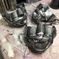 three metal masks sitting on a table