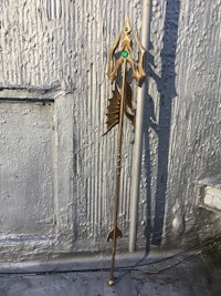 a gold statue of a mermaid leaning against a wall